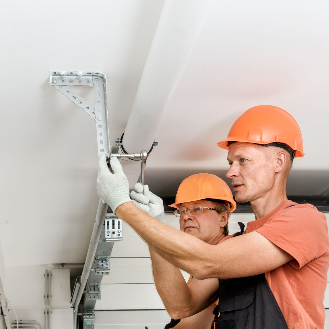 Two technicians in hard hats installing garage door track