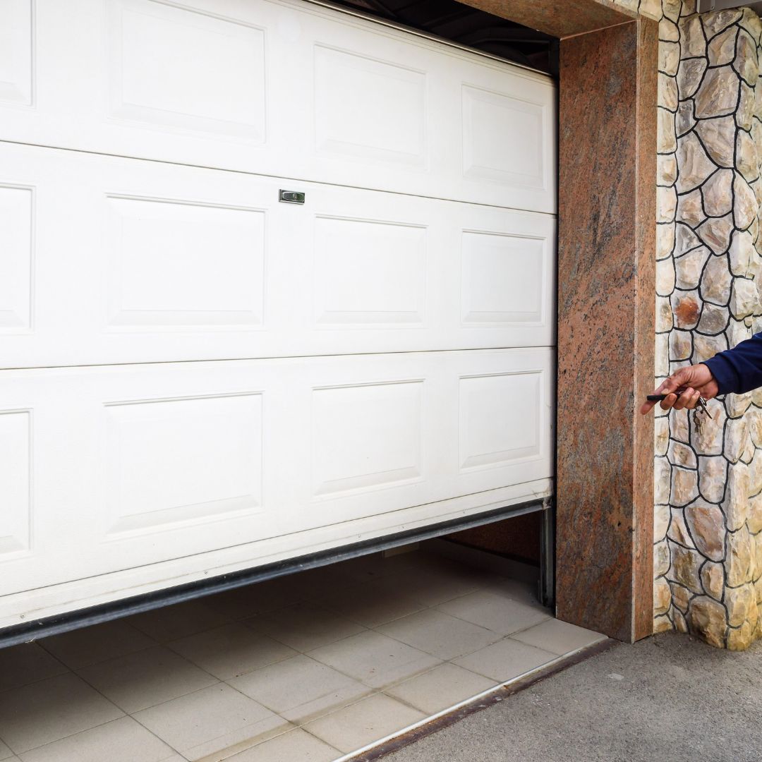 White residential garage door beside a stone wall