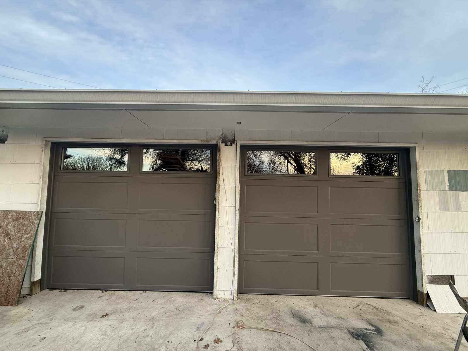 Two new Clopay Bridgeport 8x7 insulated garage doors with top windows replacing old doors on a home in Seguin, TX