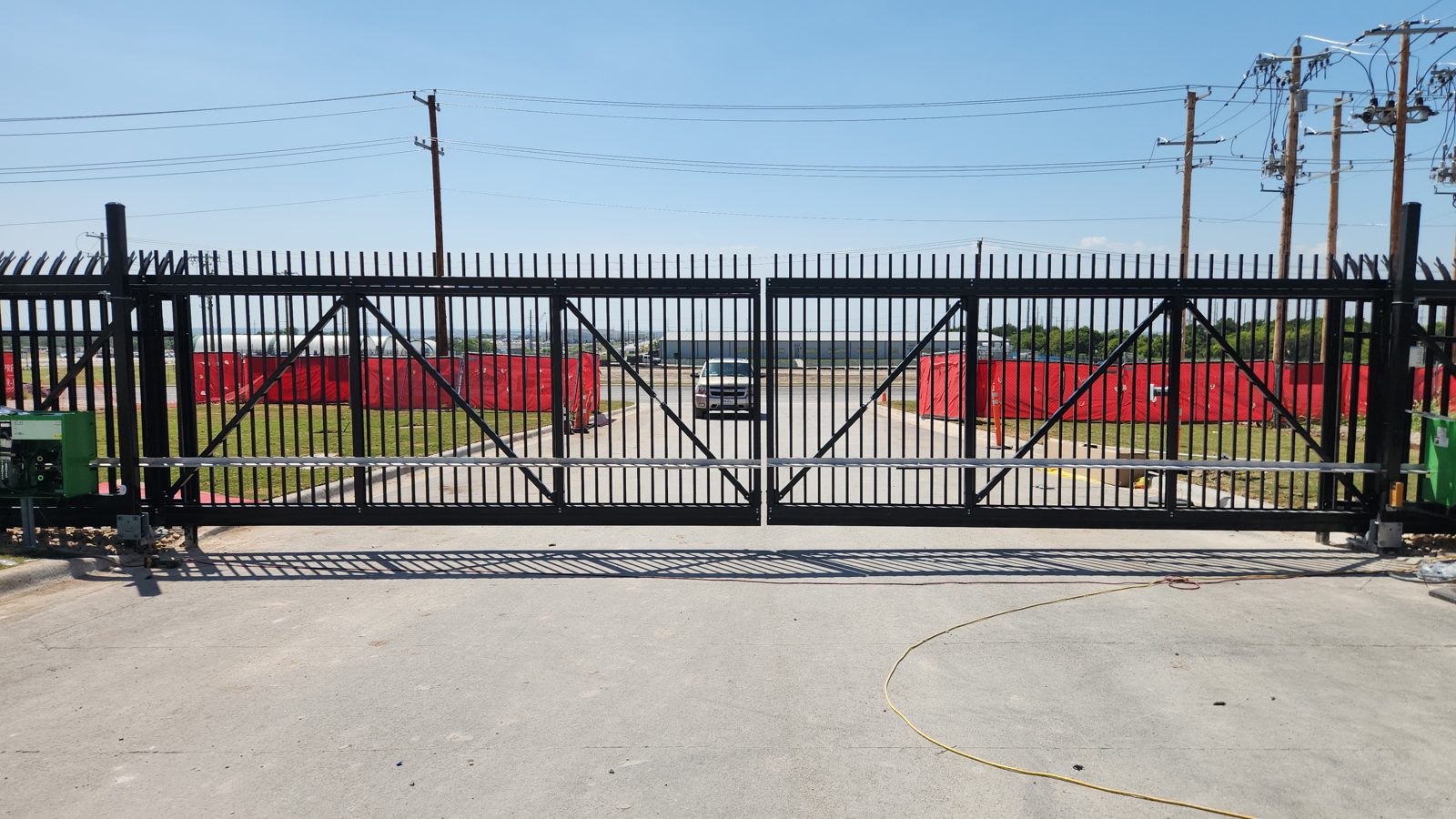Black steel bi-parting cantilever slide gate with two gate operators at a commercial entrance in Buda, TX