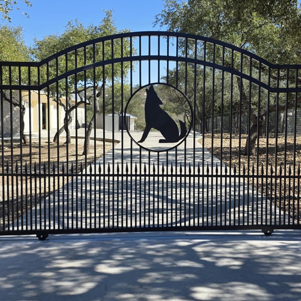 Custom black steel sliding gate with a wolf cutout built from scratch by our in-house crew in New Braunfels, TX